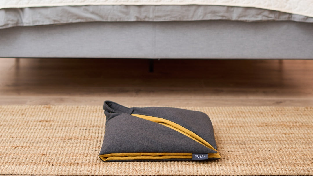 SUMA Fold ergonomic meditation cushion on a bedroom jute rug
